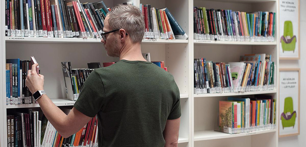 Person vänd mot en bokhylla full med böcker.