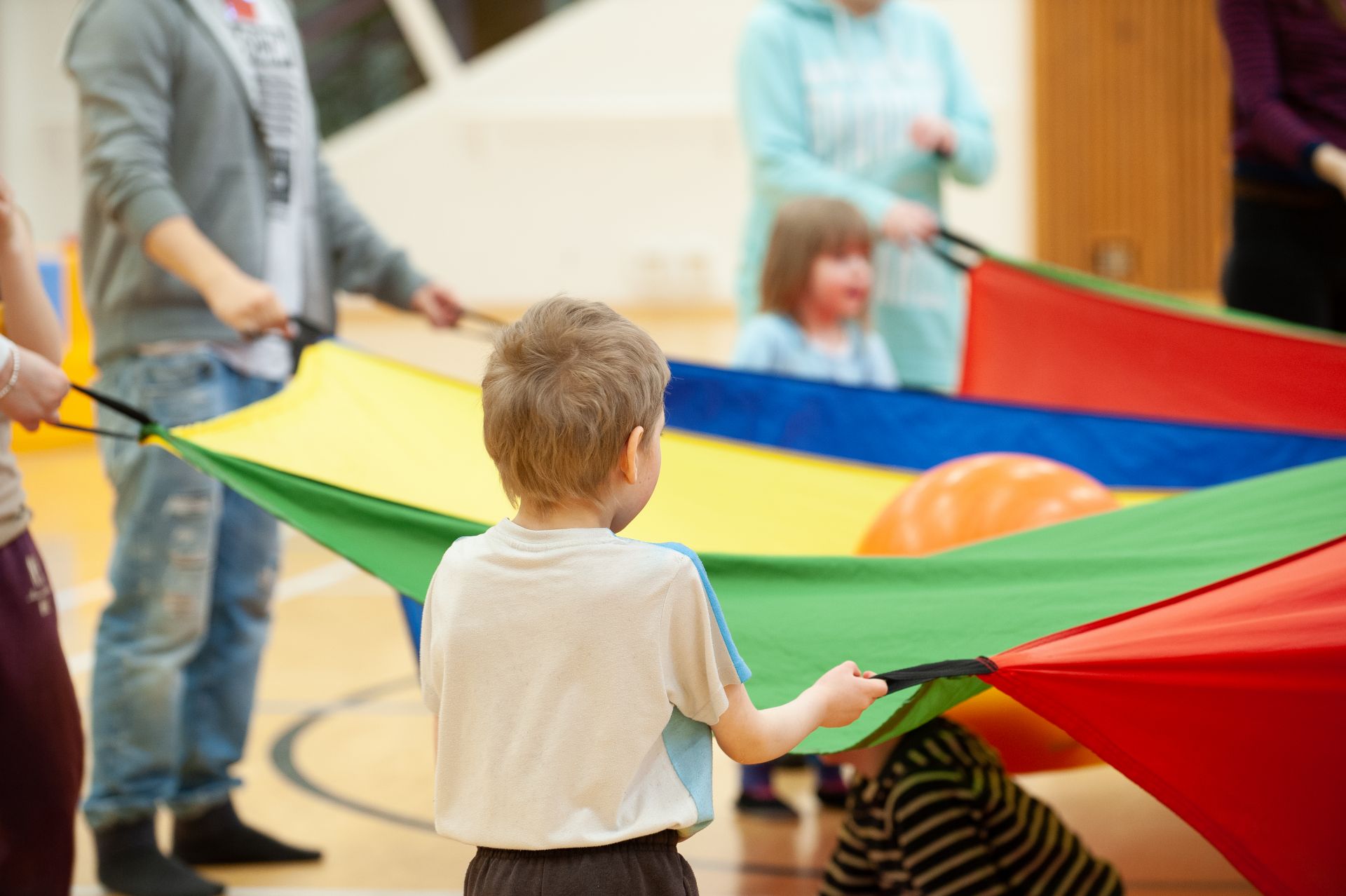 Barn och vuxna som leker med ett färggrant tyg.
