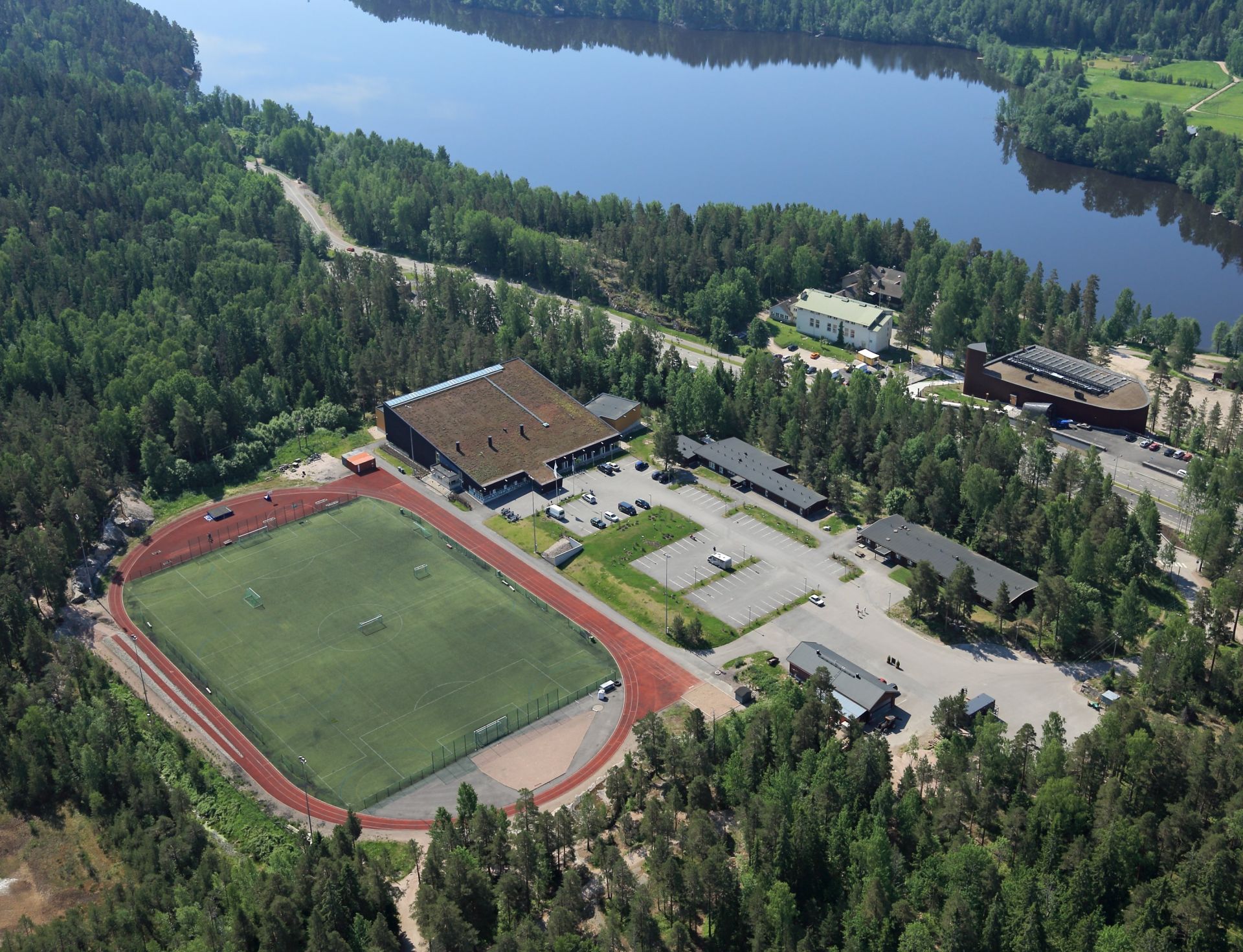 Solvalla invid en långsmal sjö och med sin idrottsplan fotat från luften.