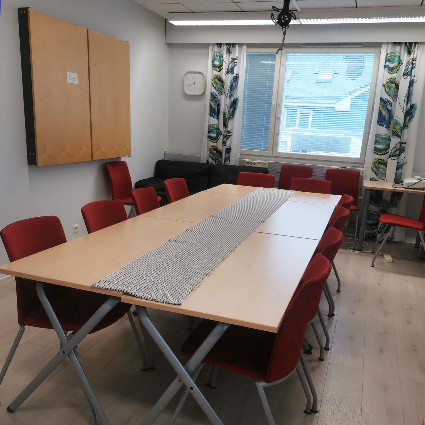 Ett mötesbord med röda stolar runt.