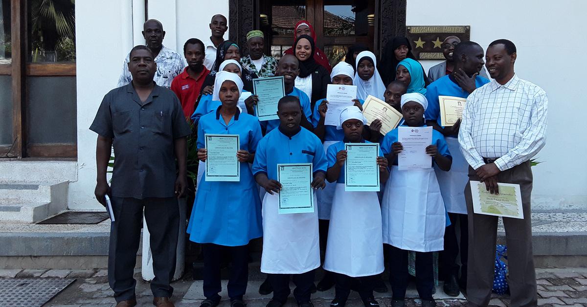 Unga zambier med intellektuell funktionsnedsättning med diplom i handen efter avlutad praktik tillsammans med föräldrar och handledare.