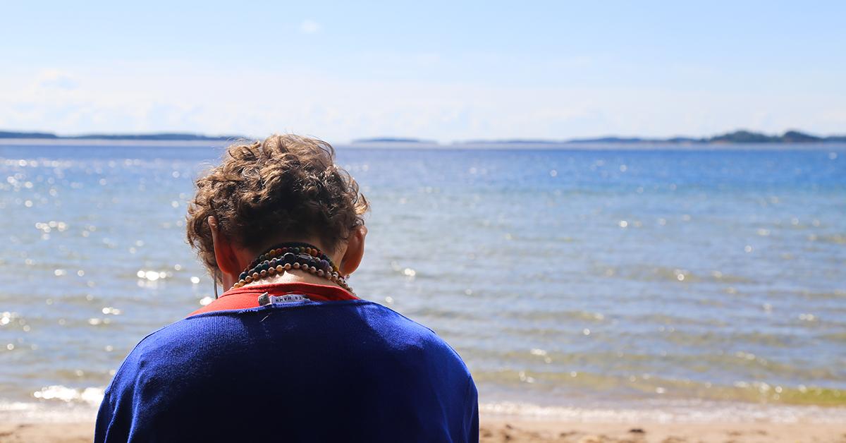 Ensam kvinna på solig sandstrand.