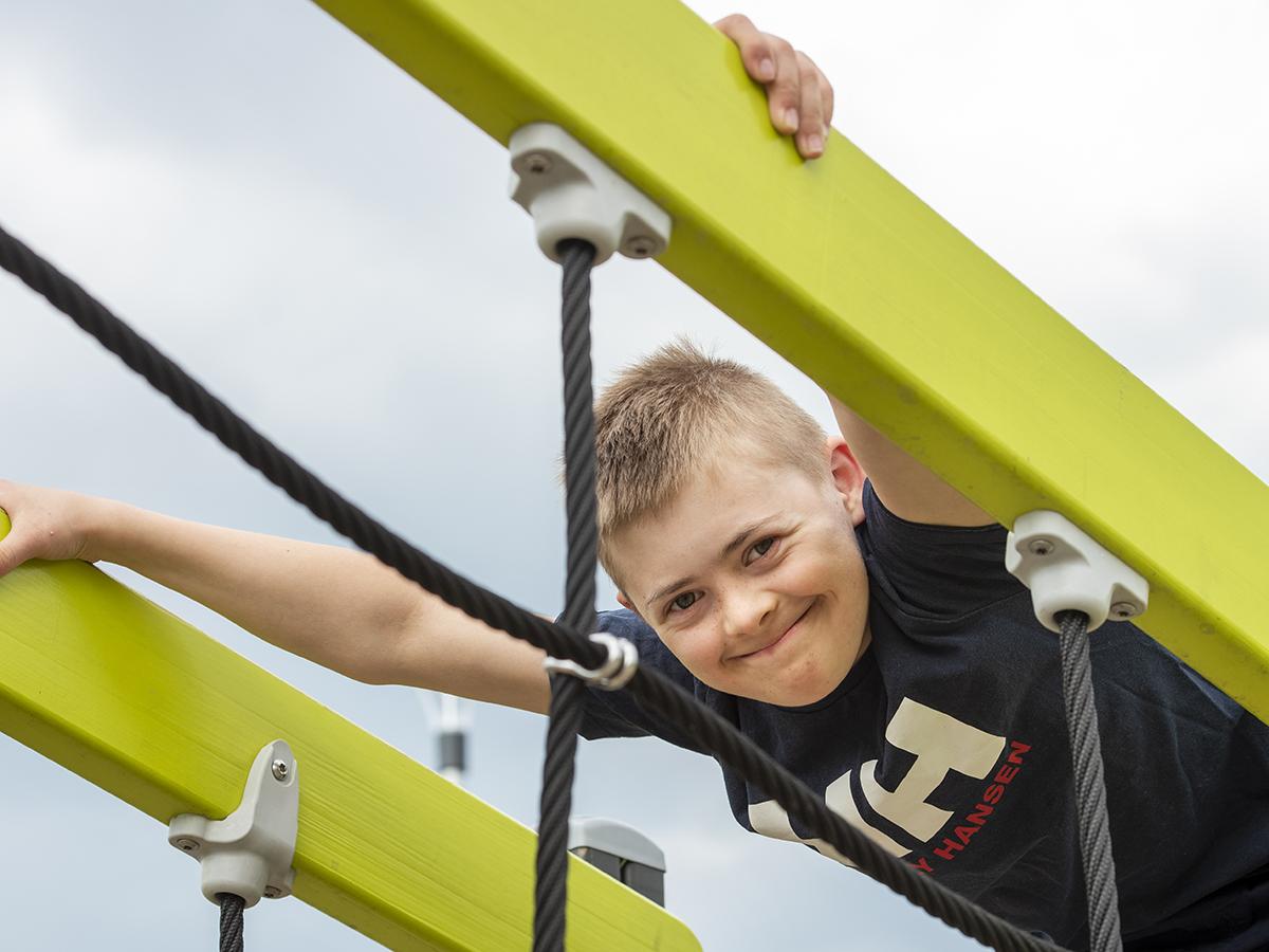 Pojke med Downs syndrom i en klätterställning.