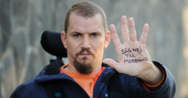 Person i rullstol håller upp en hand med texten säg nej till mobbning