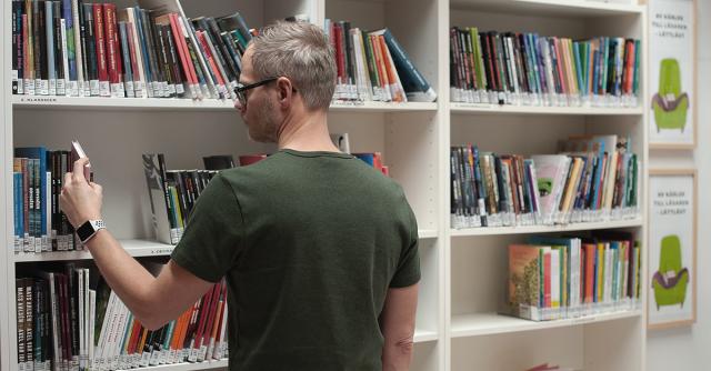 En man tar ut en bok från en hylla i FDUV:s bibliotek.