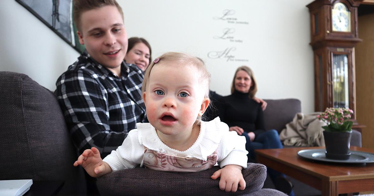 Jens Mård med sin dotter Saga i famnen. I bakgrunden sitter mamma Anne Mård och familjestödjaren Anki Byggmästar.