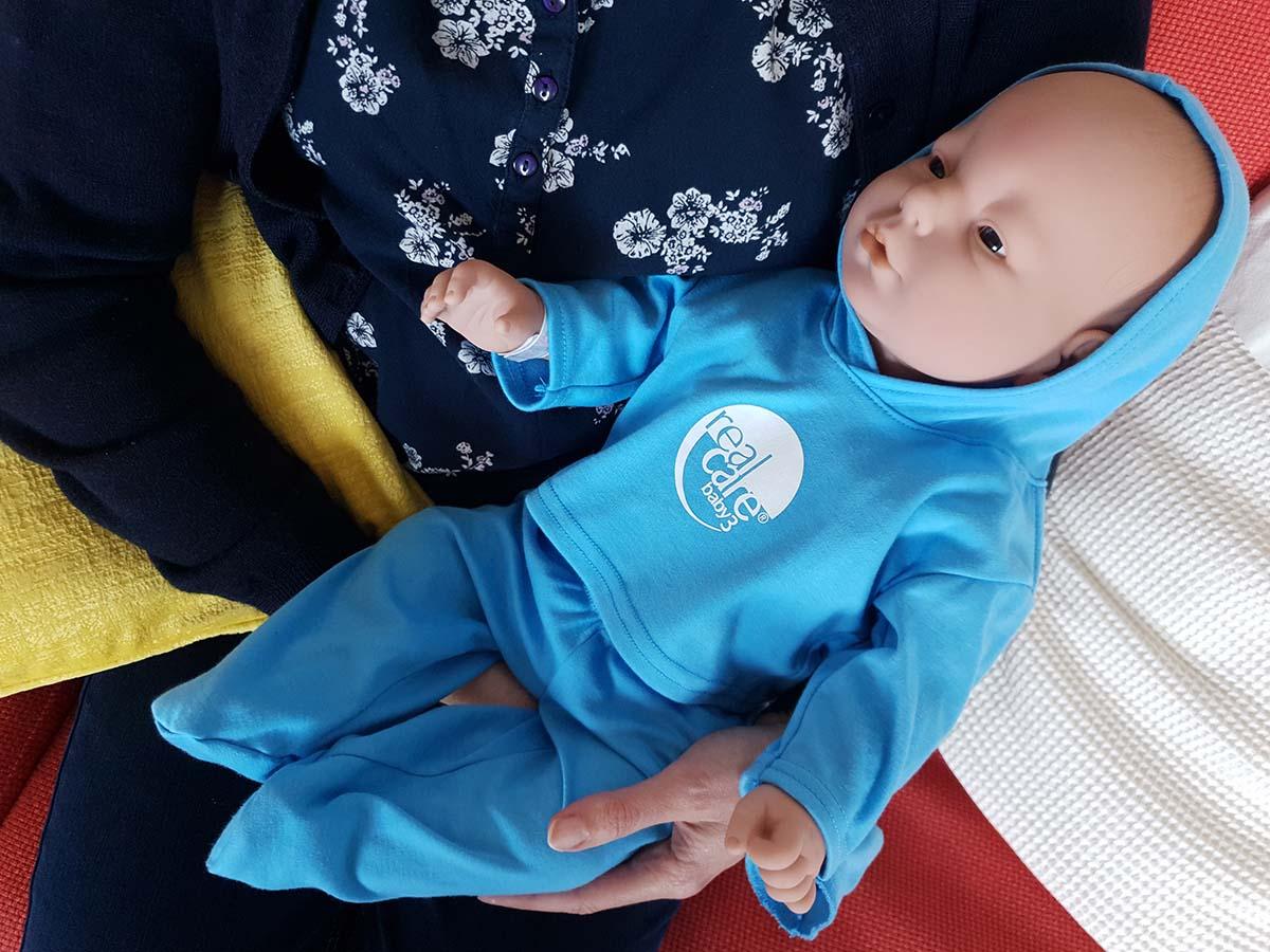 En docka som ser ut som en levande baby i famnen på en kvinna.