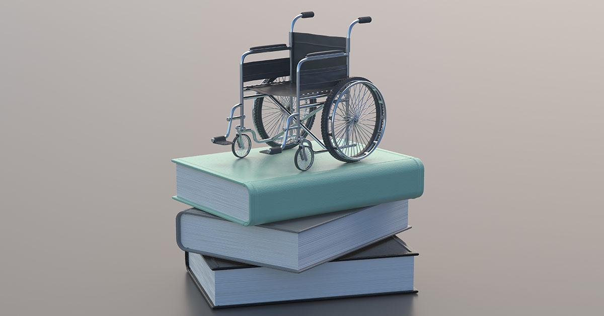 En miniatyr rullstol på en hög av böcker.