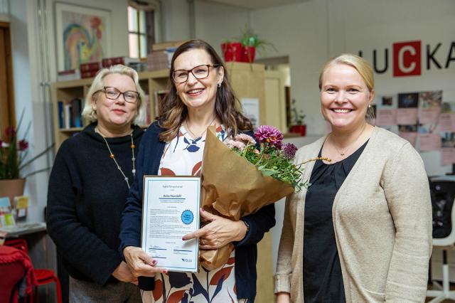 Tre kvinnor i mitten Anita Norrdahl med blommor och diplom i handen.